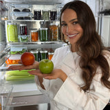 PLP Women smiling standing in front of fridge holding an apple and orange